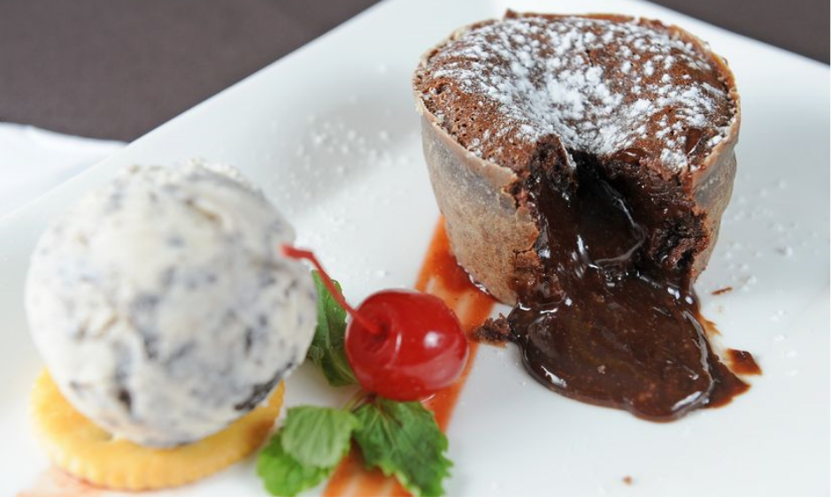 um prato de petit gateau com uma bola de sorvete e uma cereja